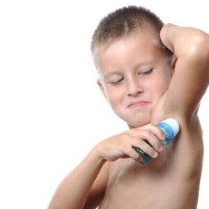 Menino utilizando um desodorante em formato roll-on sob um fundo branco. Menino utilizando um desodorante em formato roll-on sob um fundo branco.