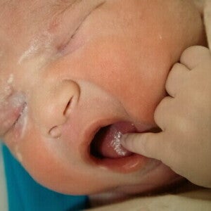 Close-up de um recém-nascido, com uma mãozinha na boca.