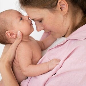 Mulher segurando seu bebê recém-nascido no colo, compartilhando um momento de ternura entre mãe e filho Mulher segurando seu bebê recém-nascido no colo, compartilhando um momento de ternura entre mãe e filho