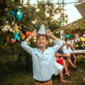 menino sorridente colocando chapéu de aniversário em festa de criança menino sorridente colocando chapéu de aniversário em festa de criança