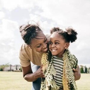 Mãe e filha rindo abraçadas em um campo de futebol Mãe e filha rindo abraçadas em um campo de futebol