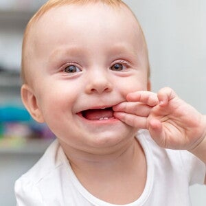 Bebê engatinhando no chão e com a mão na boca sorrindo. Bebê engatinhando no chão e com a mão na boca sorrindo.