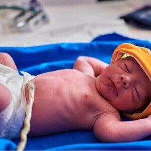 Um bebê recém-nascido deitado e de olhos fechados, ainda com o cordão umbilical Um bebê recém-nascido deitado e de olhos fechados, ainda com o cordão umbilical
