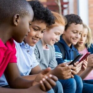 Crianças sorridentes com aproximadamente 10 anos de idade mexendo em seus celulares. Crianças sorridentes com aproximadamente 10 anos de idade mexendo em seus celulares.