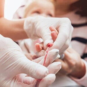 Mãe segurando bebê enquanto enfermeira colhe sangue para exame. Mãe segurando bebê enquanto enfermeira colhe sangue para exame.