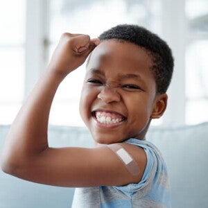 menino feliz sorri com braço levantado e um band-aid menino feliz sorri com braço levantado e um band-aid