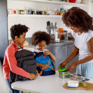 duas crianças com suas mochilas aguardam mãe fechar suas lancheiras duas crianças com suas mochilas aguardam mãe fechar suas lancheiras