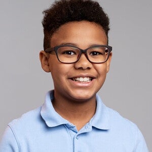 Menino vestindo camisa azul e usando óculos, sorrindo Menino vestindo camisa azul e usando óculos, sorrindo