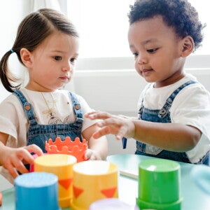 imagem de duas crianças pequenas vestindo macacão jeans e camiseta branca, brincando com brinquedos pedagógicos. imagem de duas crianças pequenas vestindo macacão jeans e camiseta branca, brincando com brinquedos pedagógicos.