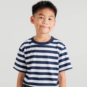 Menino asiático vestindo camiseta listrada em frente a uma parede clara Menino asiático vestindo camiseta listrada em frente a uma parede clara