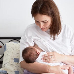 mãe amamenta bebê sentada em cama mãe amamenta bebê sentada em cama