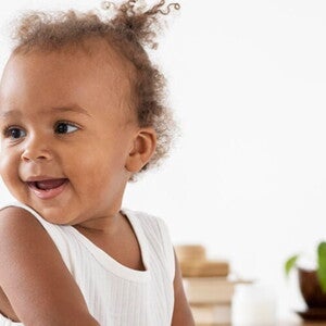 Bebê de perfil sorrindo e vestindo blusa branca Bebê de perfil sorrindo e vestindo blusa branca