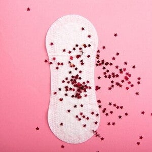 Absorvente sobreposto com várias estrelinhas vermelhas, sob um fundo rosa Absorvente sobreposto com várias estrelinhas vermelhas, sob um fundo rosa