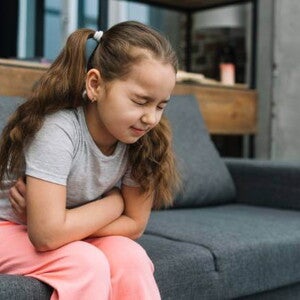 menina com esofagite com os braços cruzados na barriga sofrendo de dor abdominal menina com esofagite com os braços cruzados na barriga sofrendo de dor abdominal