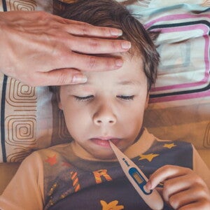 menino com febre com os olhos fechados e termômetro na boca menino com febre com os olhos fechados e termômetro na boca