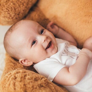 Moleira do bebê: como identificar se está normal, quando fecha e cuidados importantes bebê sorrindo, vestindo body branco