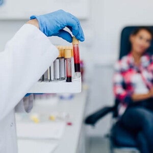 Mulher manuseando tubos de ensaio com amostras de sangue Mulher manuseando tubos de ensaio com amostras de sangue