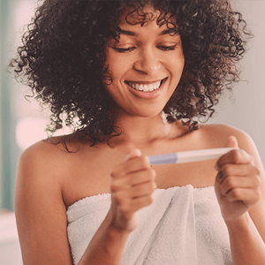 Smiling woman wrapped in a towel looking at a pregnancy test. Smiling woman wrapped in a towel looking at a pregnancy test.