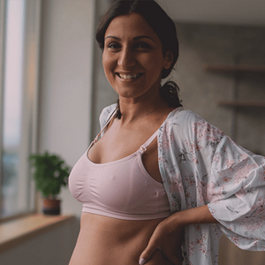 Confident looking woman in a lactation bra, checking her post partum body. Confident looking woman in a lactation bra, checking her post partum body.