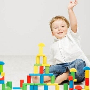 Um bebê sentado no chão com a mão para cima, em frente de diversos blocos coloridos de construir. Um bebê sentado no chão com a mão para cima, em frente de diversos blocos coloridos de construir.