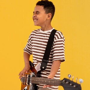Menino usando camiseta listrada tocando guitarra. Menino usando camiseta listrada tocando guitarra.