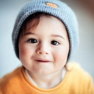 Bebê vestindo uma touca e uma roupa amarela sob um fundo desfocado. Bebê vestindo uma touca e uma roupa amarela sob um fundo desfocado.