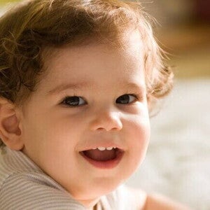 Bebê deitado e sorrindo, sendo iluminado pela luz do sol Bebê deitado e sorrindo, sendo iluminado pela luz do sol