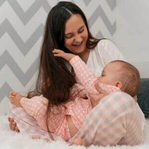 Mãe brincando com seu bebê sorridente em um ambiente acolhedor Mãe brincando com seu bebê sorridente em um ambiente acolhedor