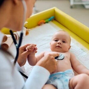 Um bebê deitado sendo examinado por uma pediatra com um estetoscópio Um bebê deitado sendo examinado por uma pediatra com um estetoscópio