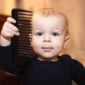 Um bebê segurando um pente de cabelo. Um bebê segurando um pente de cabelo.