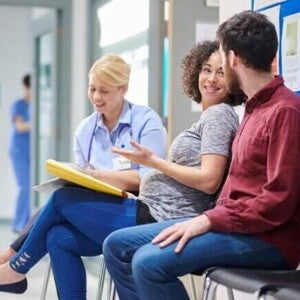Gestante conversando com médico e acompanhante em hospital