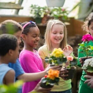 Um grupo de crianças em um jardim comunitário, segurando vasos de plantas coloridas e sorrindo enquanto participam de uma atividade de jardinagem. Um grupo de crianças em um jardim comunitário, segurando vasos de plantas coloridas e sorrindo enquanto participam de uma atividade de jardinagem.