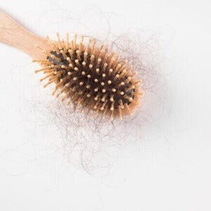 Uma escova de cabelo de madeira, com bastante cabelo preso aos seus dentes, sobre um fundo branco Uma escova de cabelo de madeira, com bastante cabelo preso aos seus dentes, sobre um fundo branco
