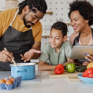 homem e mulher com uma criança ao meio cozinham sorridentes homem e mulher com uma criança ao meio cozinham sorridentes