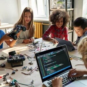 Grupo de crianças sentadas em uma mesa com várias ferramentas tecnológicas. Grupo de crianças sentadas em uma mesa com várias ferramentas tecnológicas.