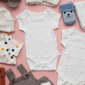 Roupas de bebê diversas, dispostas sobre uma superfície rosa. Roupas de bebê diversas, dispostas sobre uma superfície rosa.