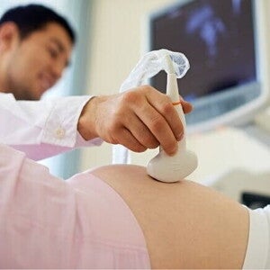 Uma mulher grávida passa por um exame de ultrassom realizado por um profissional de saúde Uma mulher grávida passa por um exame de ultrassom realizado por um profissional de saúde