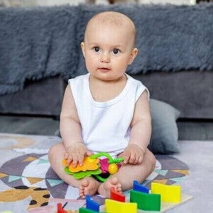 Um bebê sentado, com objetos lúdicos colocados à sua frente. Um bebê sentado, com objetos lúdicos colocados à sua frente.