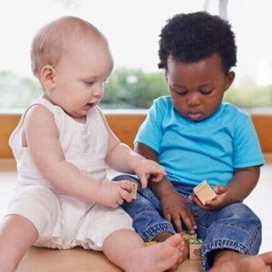Dois bebês sentados no chão, brincando com blocos de montar. Dois bebês sentados no chão, brincando com blocos de montar.