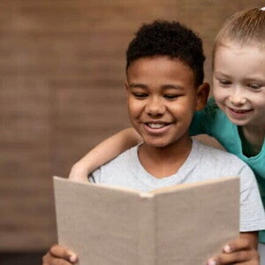 Duas crianças sorrindo, lendo um livro juntas. Duas crianças sorrindo, lendo um livro juntas.