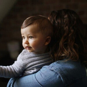 Mãe carregando um bebê de 8 meses com refluxo.