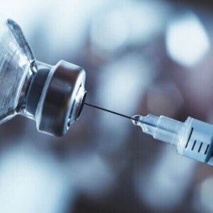 Imagem de uma seringa de vacina e um frasco de medicamento sob um fundo desfocado Imagem de uma seringa de vacina e um frasco de medicamento sob um fundo desfocado