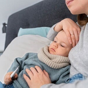 Verme infantil: sintomas, tratamento e prevenção menino sentado enquanto mulher coloca mão sobre a testa para medir temperatura