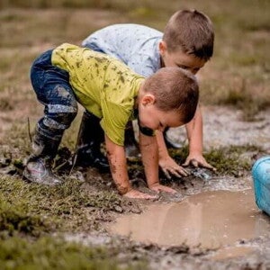 Duas crianças brincando com as mãos na lama e as roupas sujas. Duas crianças brincando com as mãos na lama e as roupas sujas.