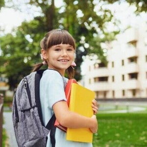 Uma menina sorrindo, segurando o material escolar e vestindo uniforme Uma menina sorrindo, segurando o material escolar e vestindo uniforme