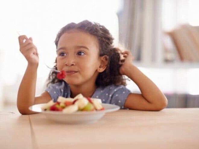 Menina vegetariana comendo um prato de frutas