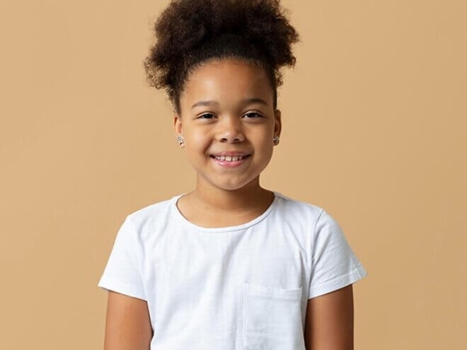 Menina com cabelo preso e camiseta branca sorrindo Menina com cabelo preso e camiseta branca sorrindo