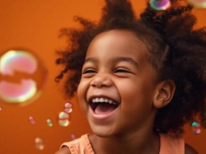 Menina sorrindo alegremente com bolhas de sabão em frente uma parede colorida Menina sorrindo alegremente com bolhas de sabão em frente uma parede colorida