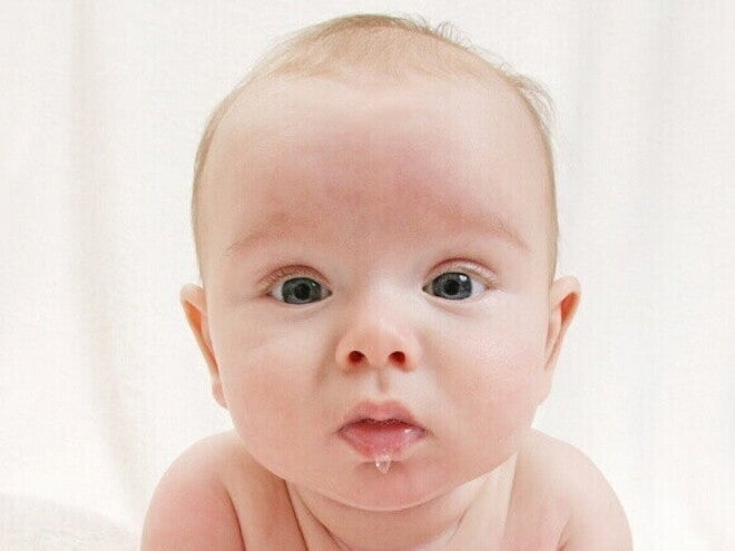 Bebê com um olhar sério babando, sob um fundo claro e iluminado. Bebê com um olhar sério babando, sob um fundo claro e iluminado.