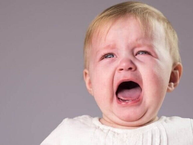 Um bebê chorando com a boca aberta, sobre um fundo lilás. Um bebê chorando com a boca aberta, sobre um fundo lilás.